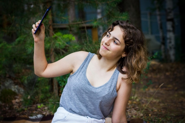 Photo beautiful teenager girl taking a selfie at the forest. using technology