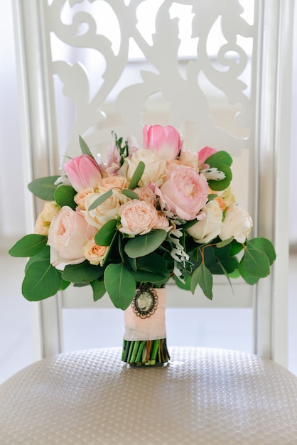 Beautiful tender wedding bouquet of roses is on the chair