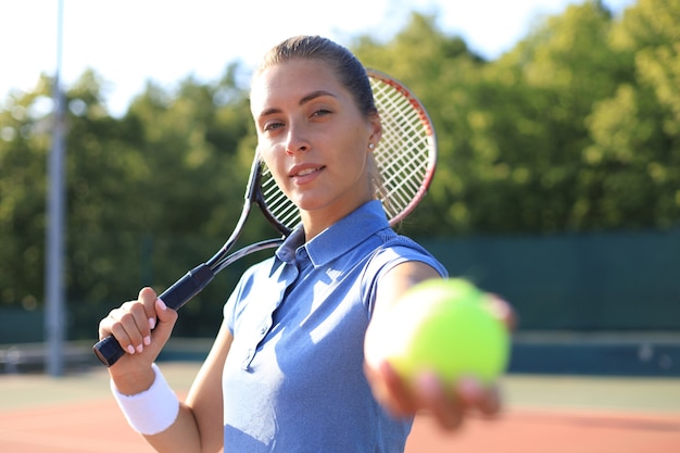 テニスコートでボールを提供する美しいテニスプレーヤー。