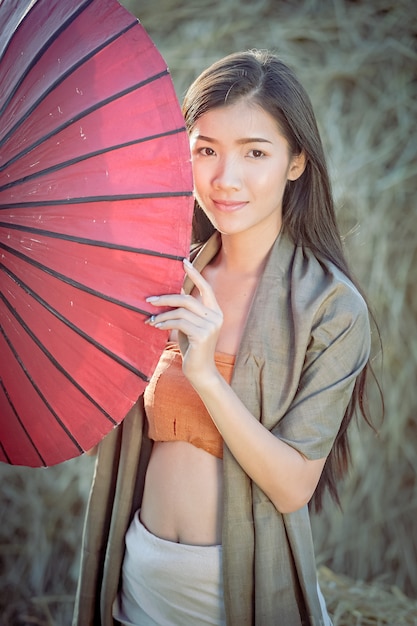 Beautiful Thai girl in traditional dress costume red umbrella