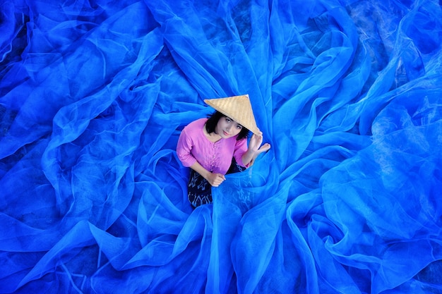 Foto la bella donna tailandese sta raccogliendo l'indaco sul pavimento netto blu