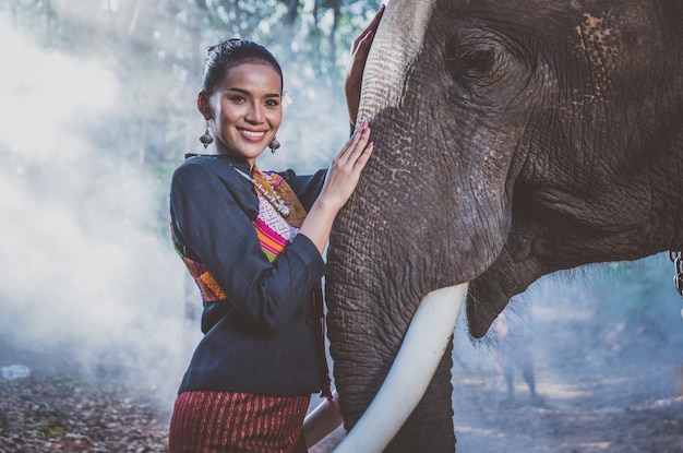 Красивая тайская женщина проводит время со слоном в джунглях