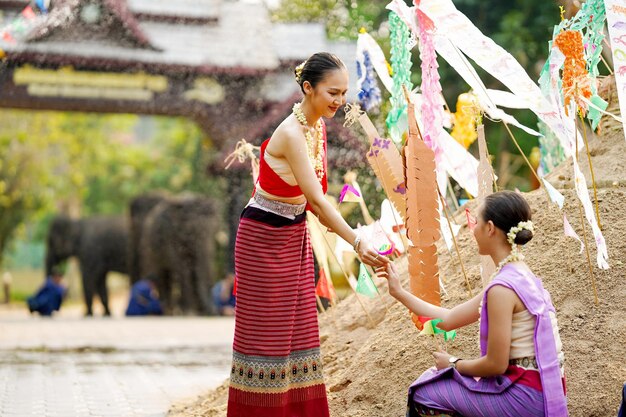 Foto bella giovane donna thailandese dare una piccola bandiera di carta ai suoi amici per aiutare posto nella sabbia