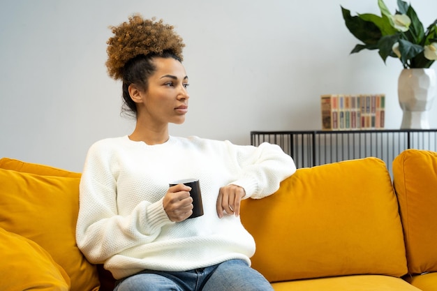 Beautiful thoughtful african american woman holding a cup of hot coffee drink enjoy the weekend at