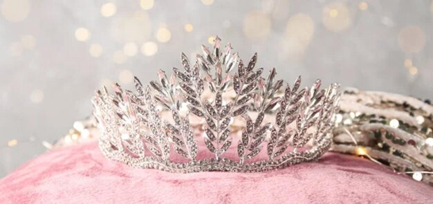 Beautiful tiara with dress on pink pillow against glowing lights