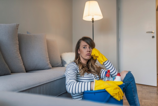 Beautiful tired woman with protective gloves wiping her forehead