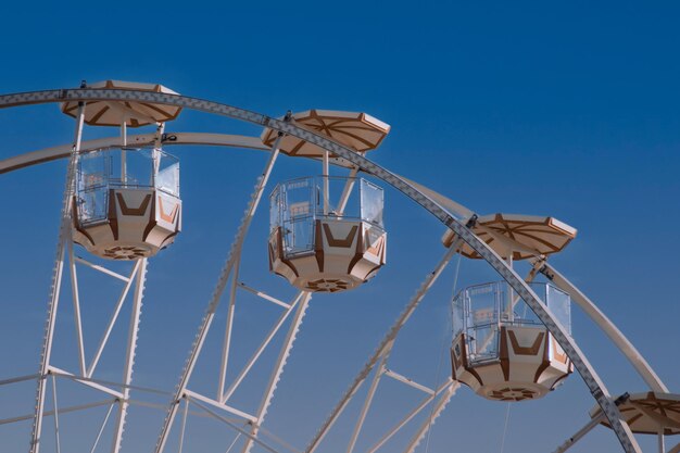 Beautiful top part of ferris wheel with cabins on blue sky background