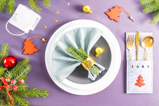 Foto bella vista dall'alto del servizio di capodanno festivo sullo sfondo grigio della tovaglia piegata a ventaglio tovagliolo su piatti decorazioni natalizie