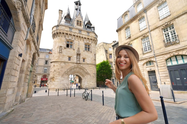 Bella ragazza turistica che visita la città di bordeaux francia donna attraente che guarda l'obbiettivo con porte cailhau porta fortificata a bordeaux in francia