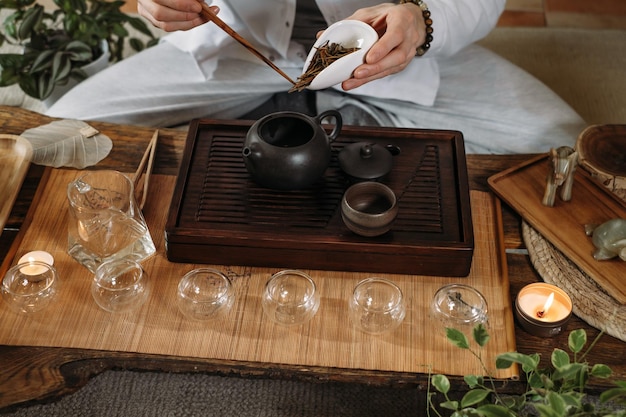 Beautiful traditional Chinese ceremony Gun Fu Cha Master pouring oolong from teapot with vapor on a dark background