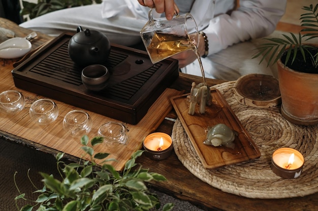 Beautiful traditional chinese ceremony gun fu cha master\
pouring oolong from teapot with vapor on a dark background