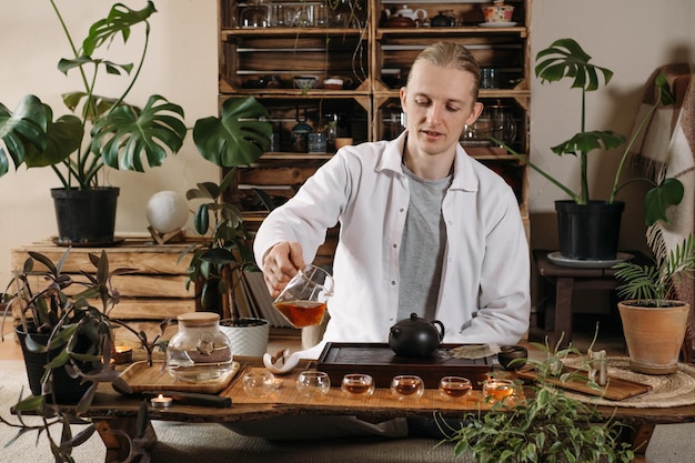 Beautiful traditional chinese ceremony gun fu cha master\
pouring oolong from teapot with vapor on a dark background