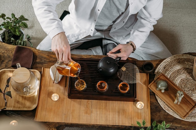 Beautiful traditional chinese ceremony gun fu cha master\
pouring oolong from teapot with vapor on a dark background