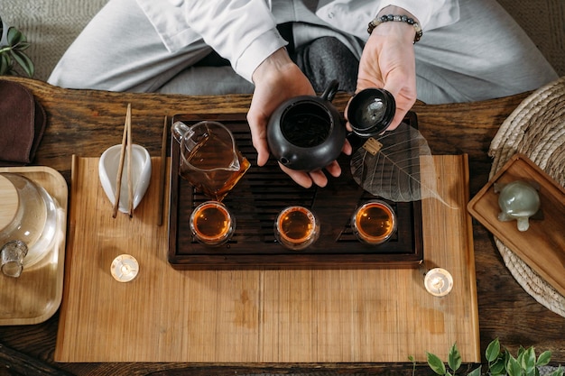 Beautiful traditional chinese ceremony gun fu cha master\
pouring oolong from teapot with vapor on a dark background