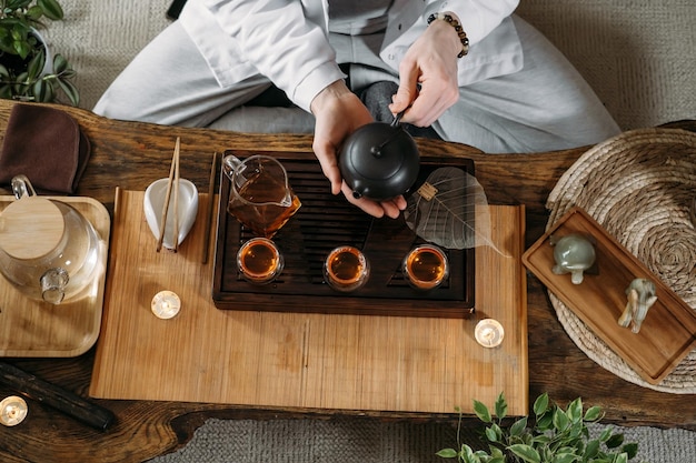 暗い背景に蒸気で急須からウーロン茶を注ぐ美しい繁体字中国語の儀式ガンフーチャマスター
