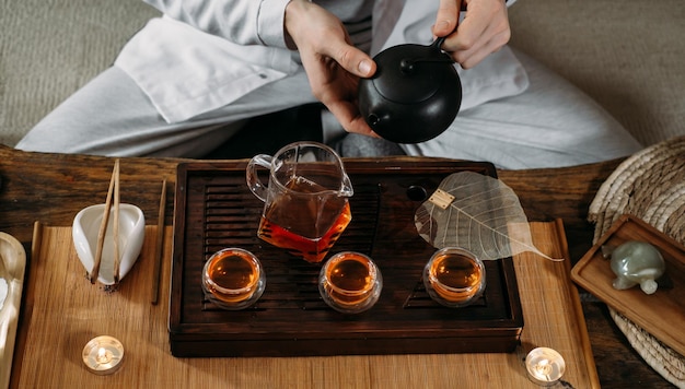 Beautiful traditional chinese ceremony gun fu cha master\
pouring oolong from teapot with vapor on a dark background