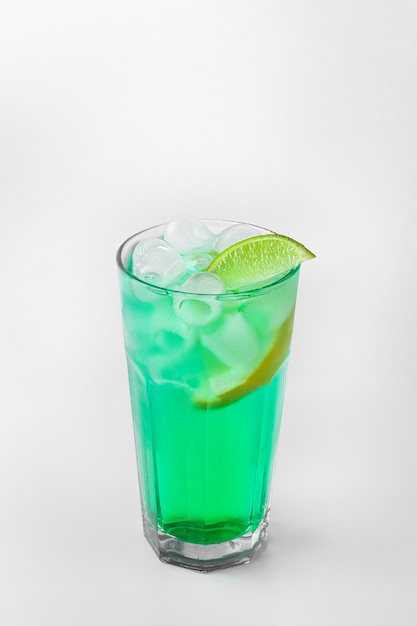 Beautiful transparent glass of summer drink. green lemonade with ice and lime isolated on a white background with natural shadows