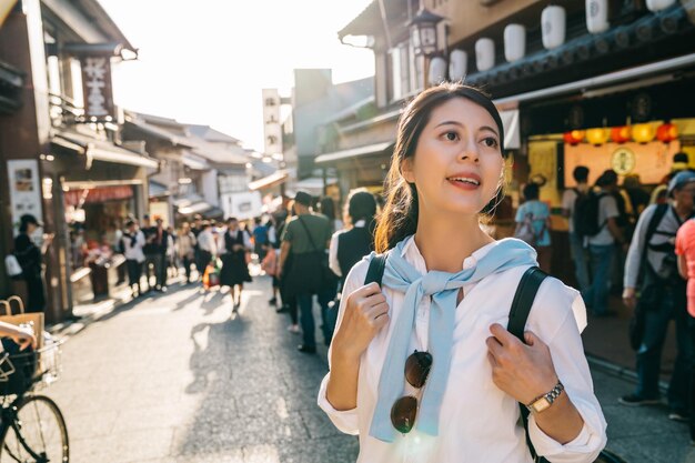 日本の賑やかな通りに立って、食べる屋台の食べ物を見つけている美しい旅行者。屋台では日本の特産品を販売。賑やかな町での日本人の休日のライフスタイル。