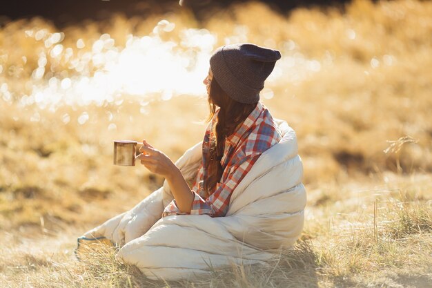 Beautiful traveler woman hiking in the mountains with a cup of drink near lake camping travel