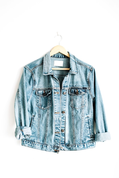 Photo beautiful trendy blue denim jeans jacket on hanger near white