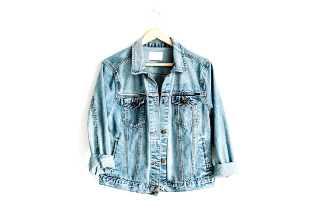 Beautiful trendy blue denim jeans jacket on hanger near white