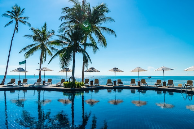 수영장과 우산과 의자가있는 아름다운 열대 해변과 바다