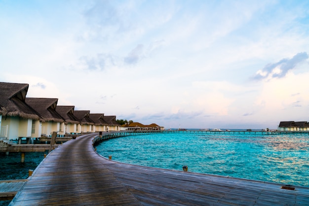 Bello tramonto tropicale sopra l'isola delle maldive con il bungalow dell'acqua nella località di soggiorno dell'hotel