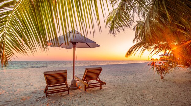 美しい熱帯の夕暮れの風景 2つの日焼けベッド 陽台 傘 パームの木の下 白い砂 海の景色と地平線 カラフルな夕暮れ 空の静けさとリラックス インスピレーションのビーチリゾートホテル