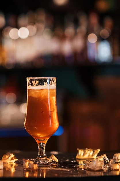 Beautiful tulip glass with foamy golden beer ale on bar counter