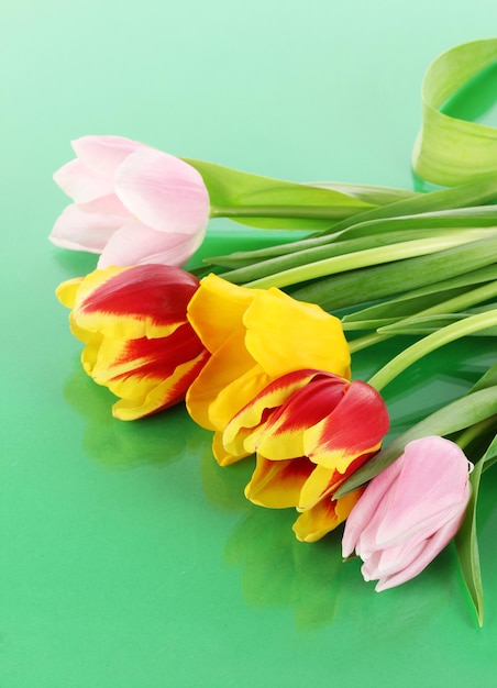 Beautiful tulips in bucket on green background