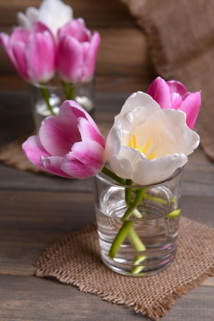 Beautiful tulips in bucket in vase on table on grey background