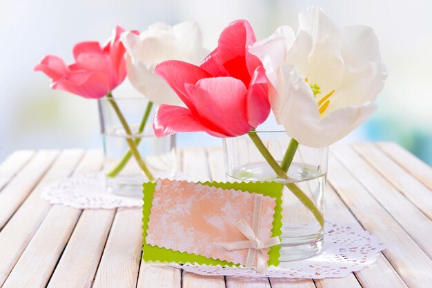 Beautiful tulips in bucket in vase on table on light background