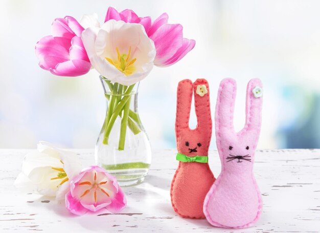 Beautiful tulips in bucket in vase on table on light background