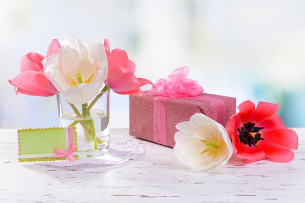 Beautiful tulips in bucket in vase on table on light background