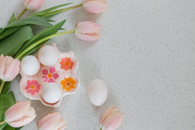 Beautiful tulips and natural eggs on modern table Stylish easter flat lay with copy space Happy Easter Handmade egg holder with pink tulips