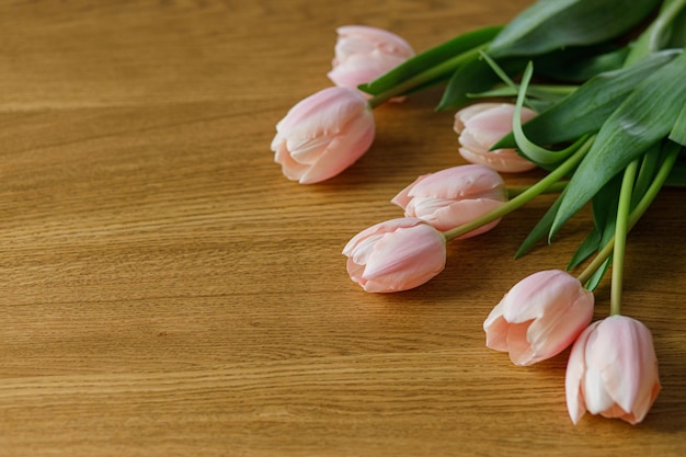 Beautiful tulips on wooden table with space for text Modern easter decor Stylish pink tulips bouquet Happy mothers day and womens day