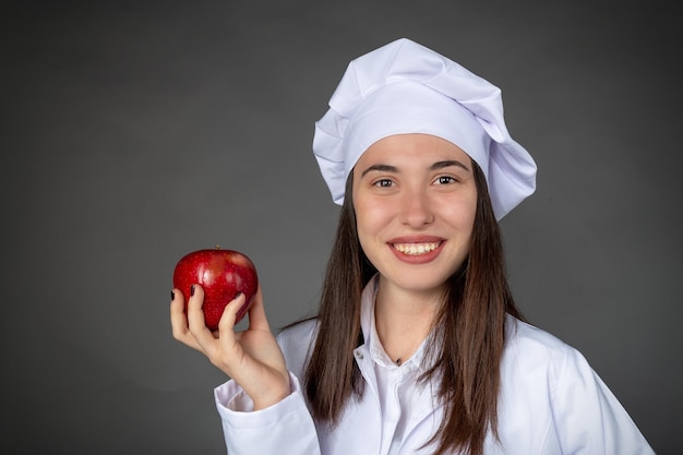 Красивая турецкая молодая женщина-повар держит яблоко в руке
