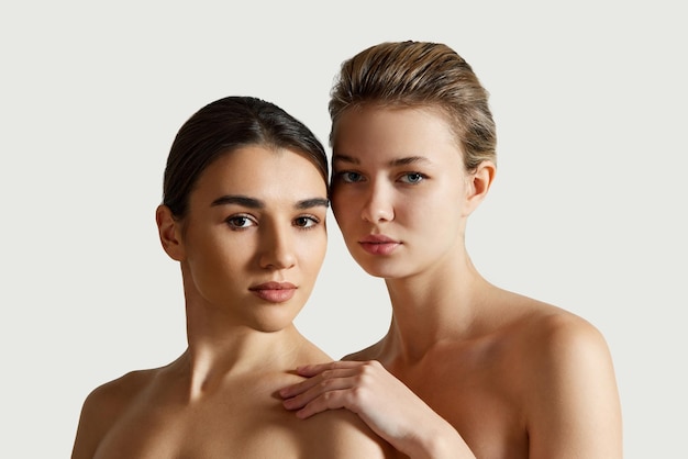 Beautiful two girls with different skin tones perfect smooth spotless skin with bare shoulders