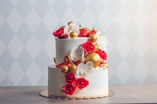 Beautiful two-tiered white wedding cake decorated with red roses