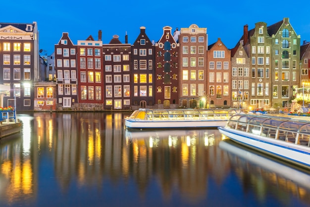 밤, 네덜란드, 네덜란드 암스테르담 운하 Damrak에서 아름 다운 전형적인 네덜란드 춤 주택과 관광 보트.