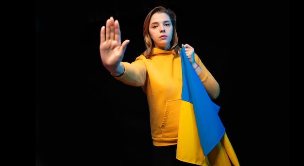 黒い背景にウクライナの国民国家旗を持つ美しいウクライナの女の子スペースをコピーロシアのウクライナ戦争助けてウクライナのために祈る戦争をやめる