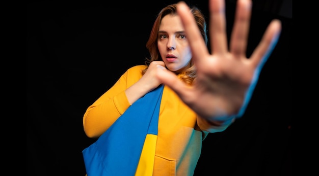 Beautiful Ukrainian girl with the national state flag of Ukraine on black background Copy space Russian Ukrainian War Help and Pray for Ukraine Stop war