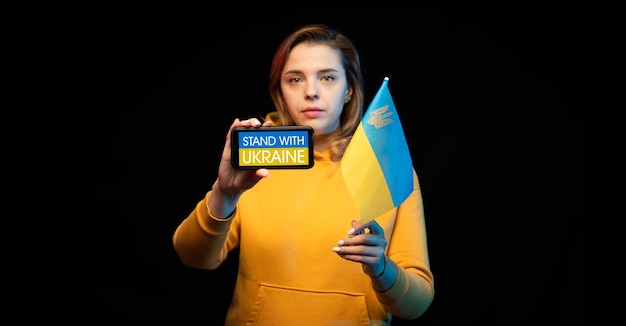 Foto bella ragazza ucraina con una bandiera di stato e uno smartphone in mano con una chiamata stand con l'ucraina il concetto reale di supporto contro la guerra russoguerra ucraina prega per l'ucraina ferma la guerra