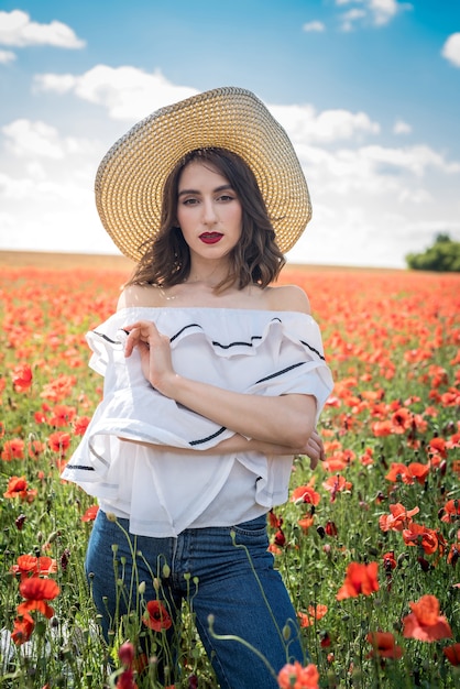 Beautiful ukrainian lady alone in straw hat at flowers poppies field