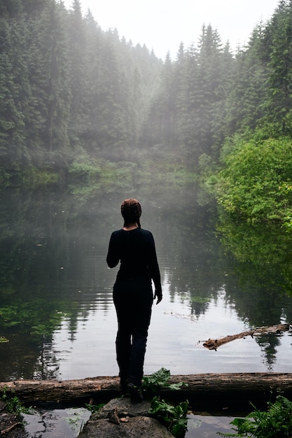 Beautiful ukrainian nature Woman standing hean forest lake surrounded with pine trees Carpathian Mountains Rosohan Ukraine