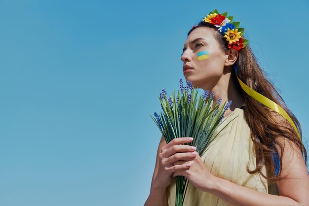 背景の空の花束を握る花の冠をかぶった美しいウクライナの女性