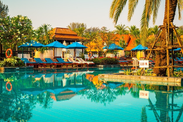 Bellissimo ombrellone e sedia intorno alla piscina in hotel e resort - concerto di vacanze e vacanze