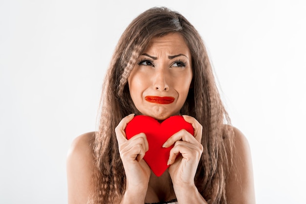 Beautiful unhappy girl crying and holding broken red heart. Valentine's Day concept.