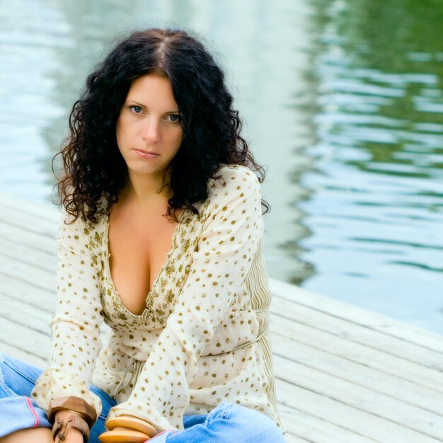 Beautiful unhappy woman sitting near the water person