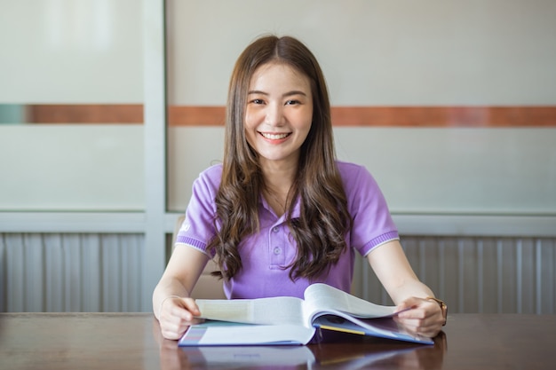 Beautiful university girl reading a book in library. Concept for learning and education.